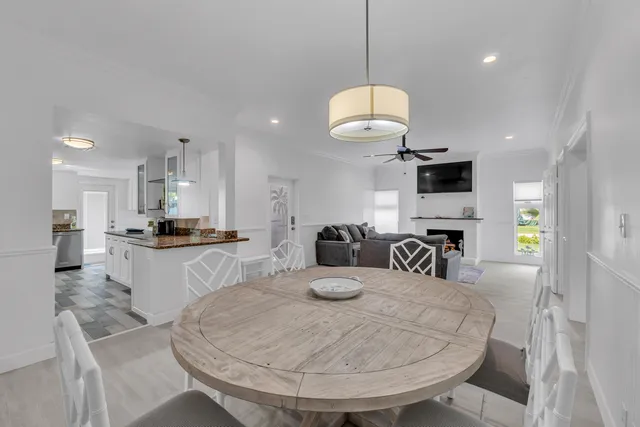 a kitchen with stainless steel appliances kitchen island granite countertop a sink a stove a dining table and chairs with wooden floor