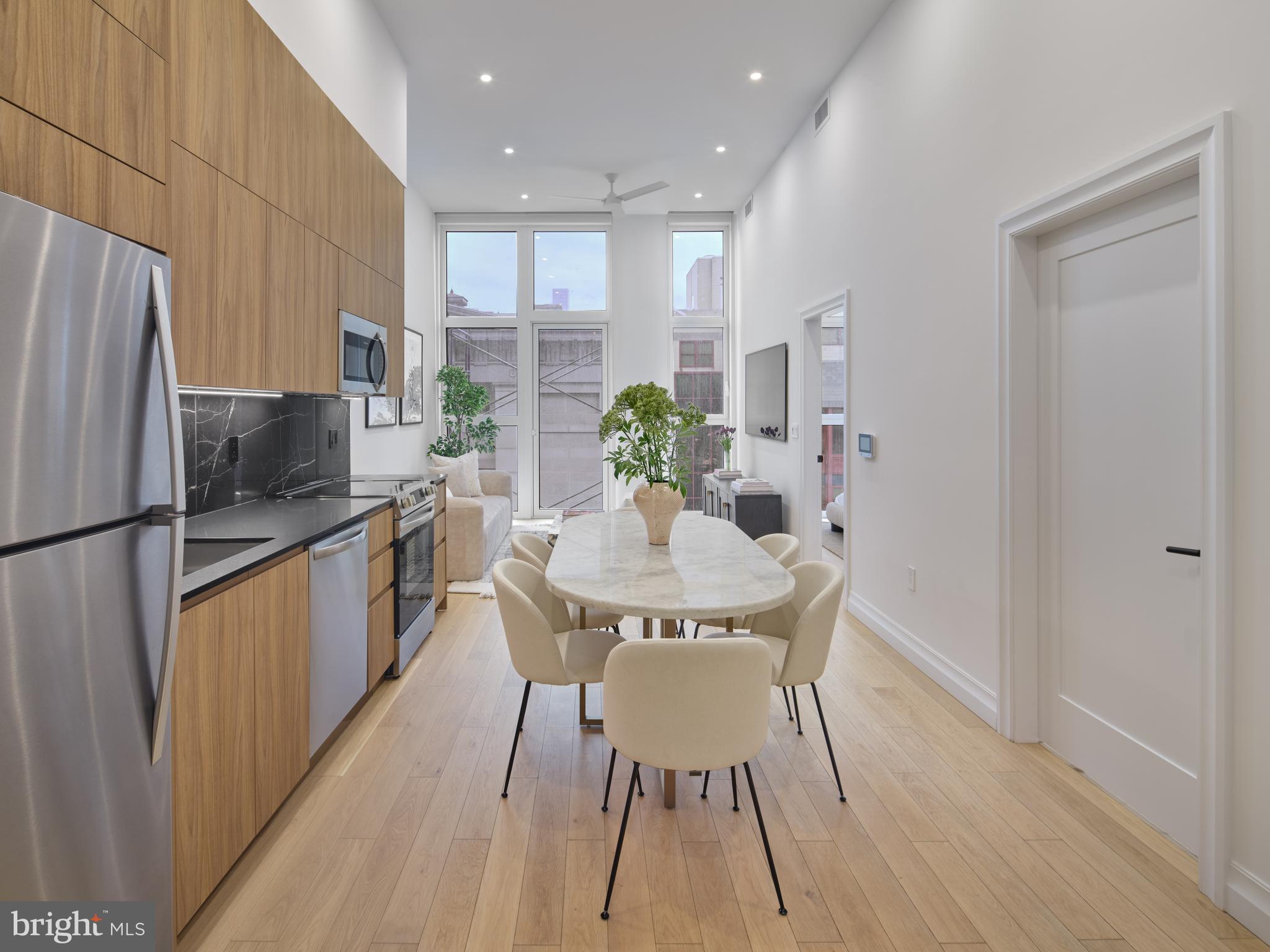 a kitchen with stainless steel appliances granite countertop a refrigerator a sink a stove a dining table and chairs