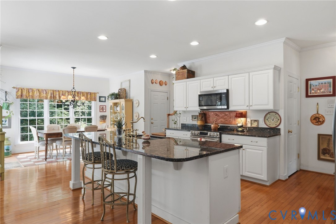 13424 Tipple Point Road Midlothian, VA 23114 - Photo 10 of 53 a kitchen with stainless steel appliances granite countertop a stove top oven a sink a dining table and chairs with wooden floor