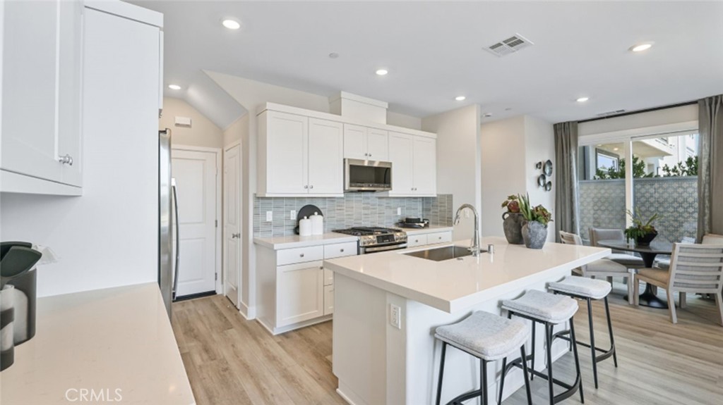 474 Lobata Irvine, CA 92618 - Photo 1 of 43 a kitchen with a stove a refrigerator and a dining table with wooden floor