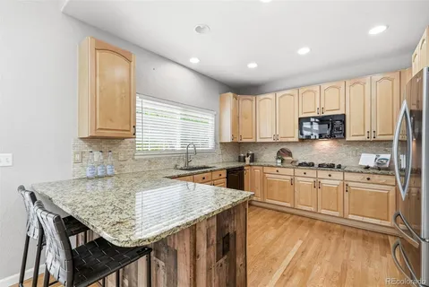 a kitchen with granite countertop kitchen island wooden cabinets a stove a sink and appliances