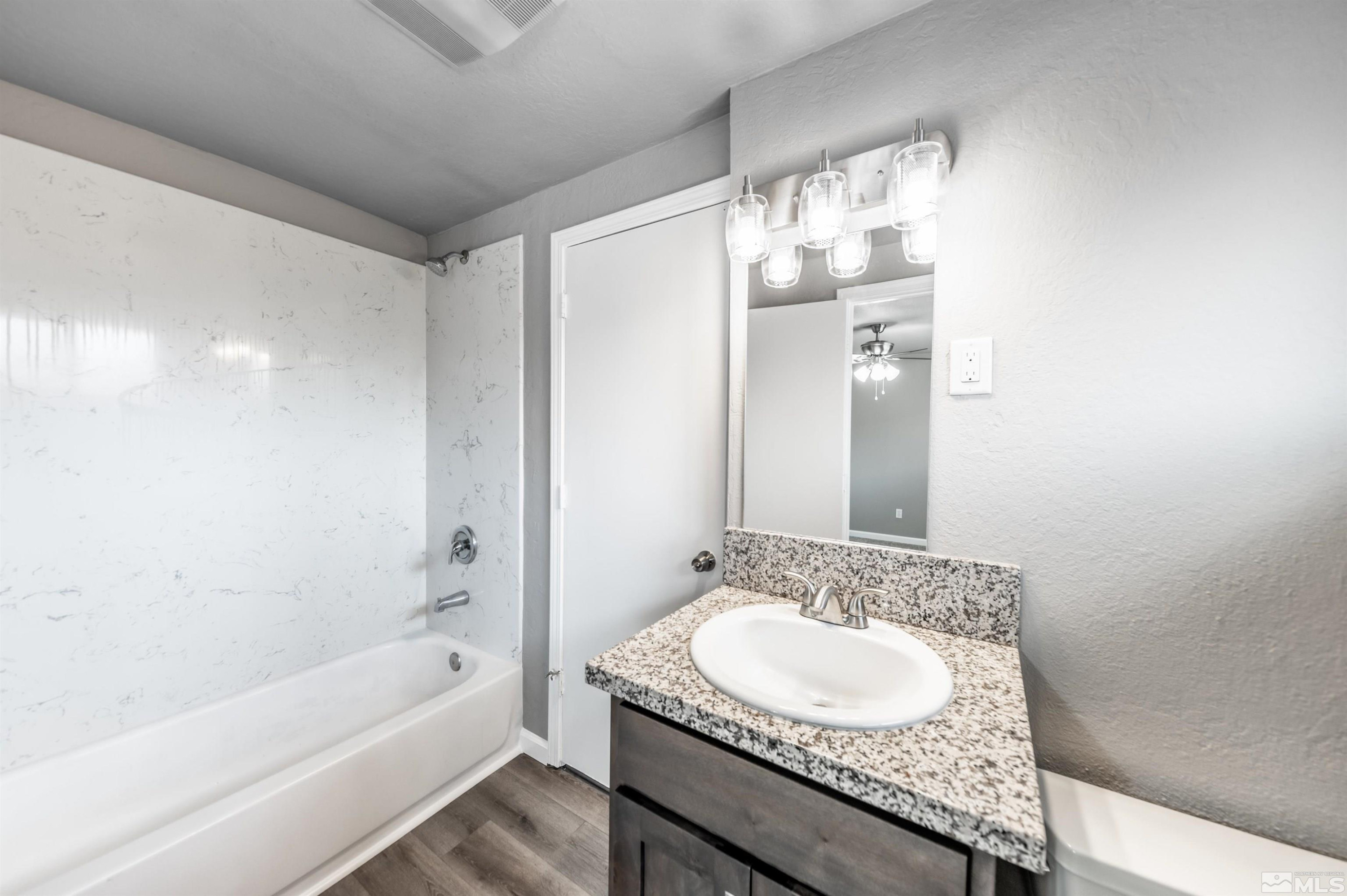 495 Kess Court Reno, NV 89506 - Photo 12 of 18 a bathroom with a granite countertop sink a mirror and a bathtub