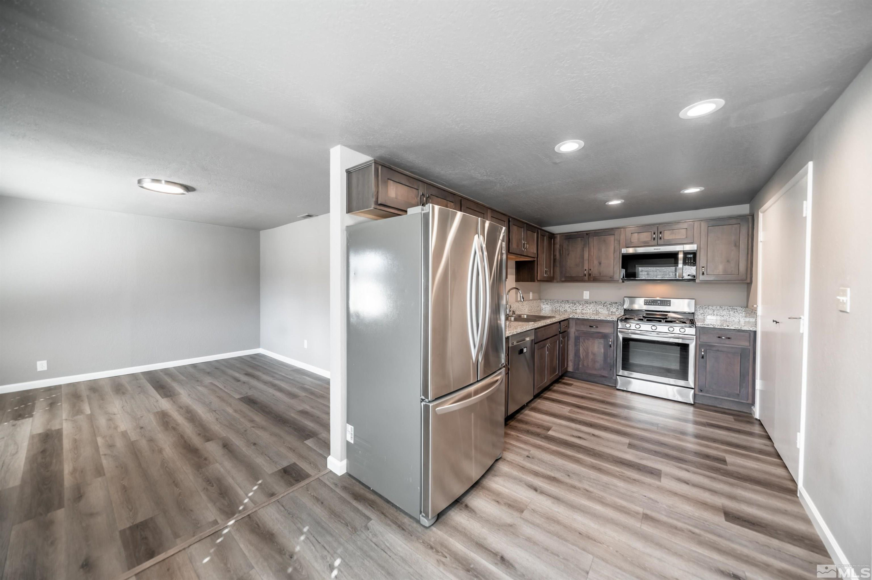 495 Kess Court Reno, NV 89506 - Photo 4 of 18 a kitchen with granite countertop a refrigerator and a stove top oven