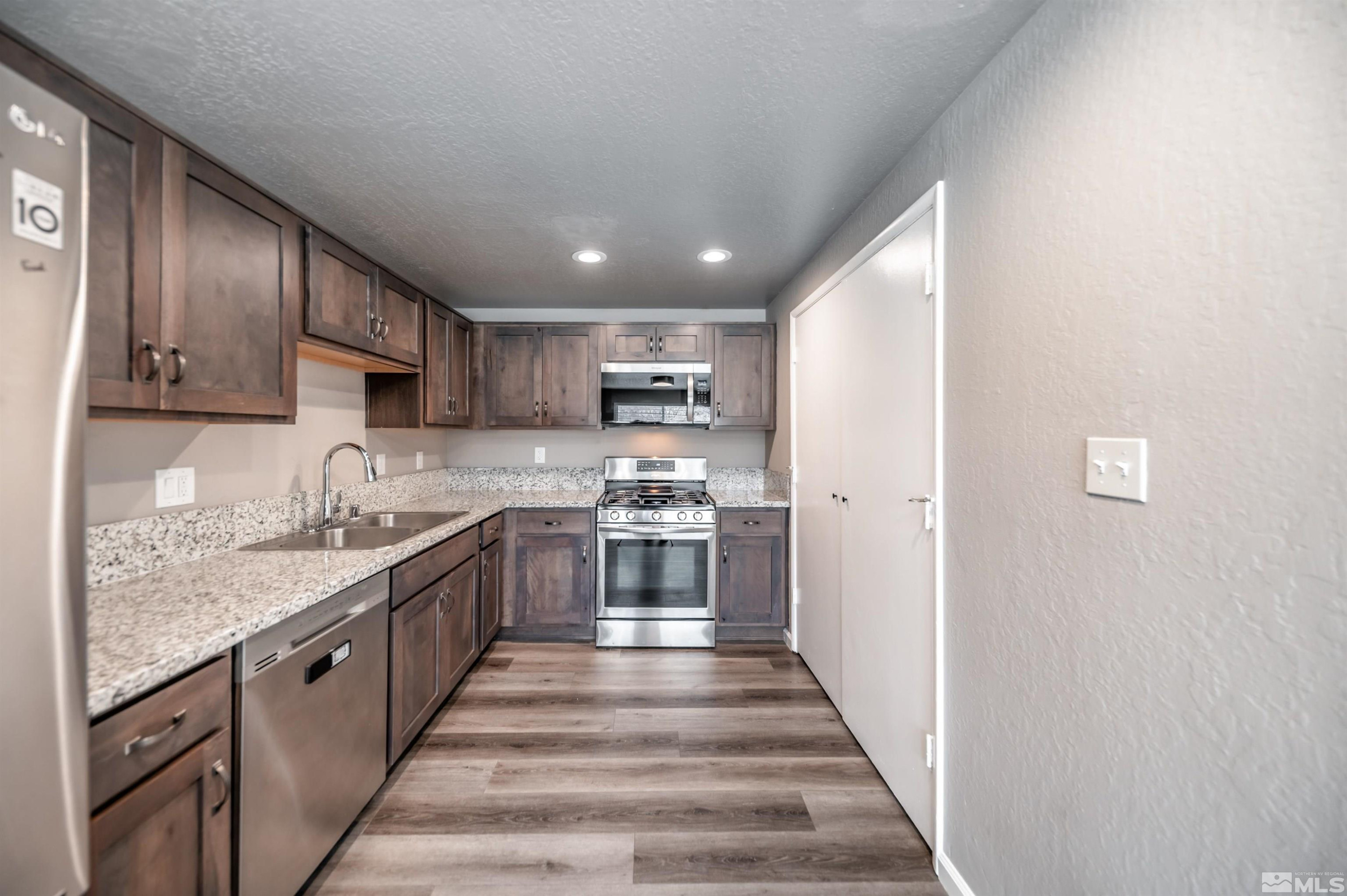 495 Kess Court Reno, NV 89506 - Photo 5 of 18 a large kitchen with stainless steel appliances granite countertop a sink and dishwasher a stove with wooden cabinets