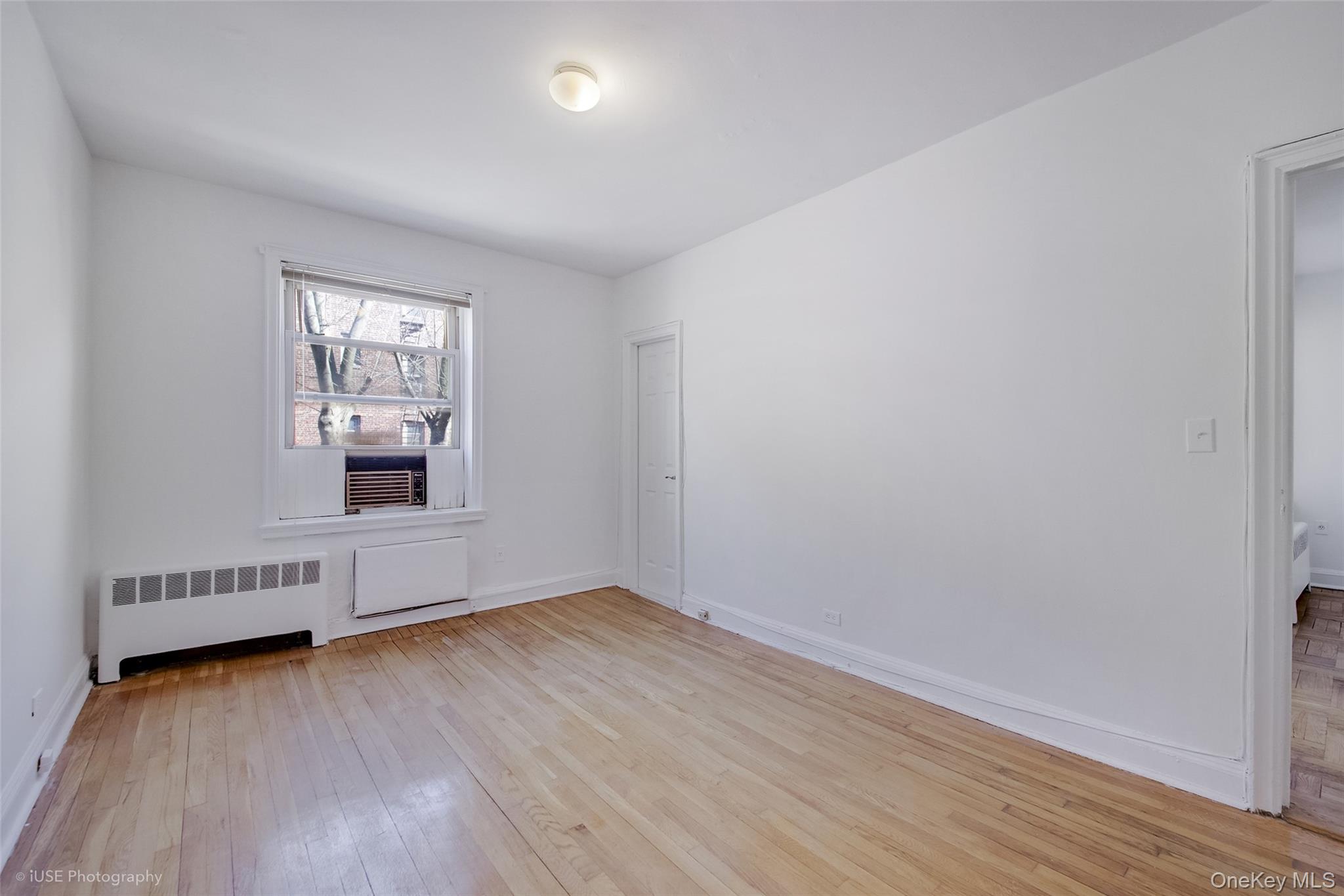 48-41 43rd Street, Unit 5F Queens, NY 11377 - Photo 4 of 8 an empty room with wooden floor and windows