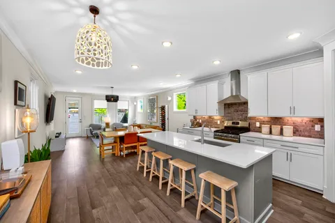 a kitchen with stainless steel appliances a stove a refrigerator a sink dishwasher and white cabinets with wooden floor