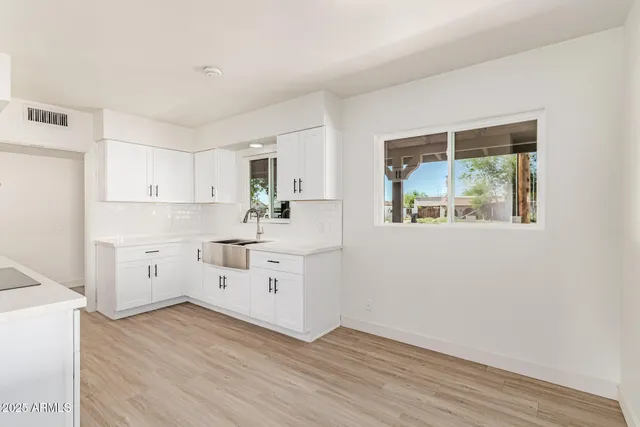 a kitchen with wooden floors and white cabinets