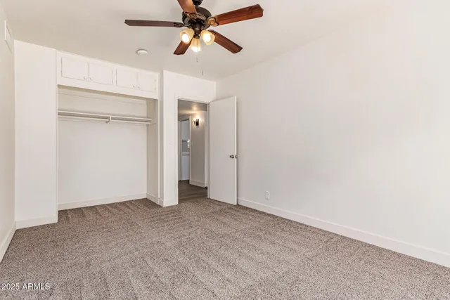 an empty room with closet and a ceiling fan