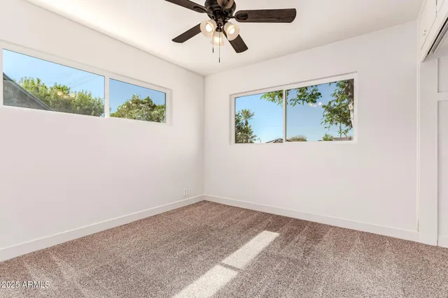 an empty room with a window and a ceiling fan