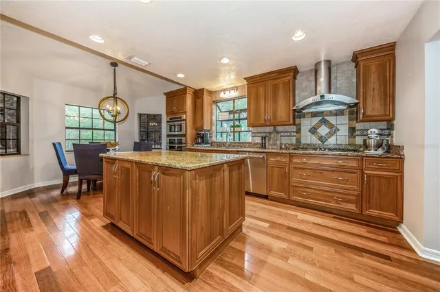 a kitchen with stainless steel appliances granite countertop a sink a stove and a wooden floors