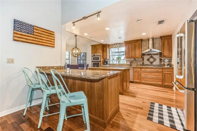 a kitchen with stainless steel appliances granite countertop a kitchen island hardwood floor and a sink