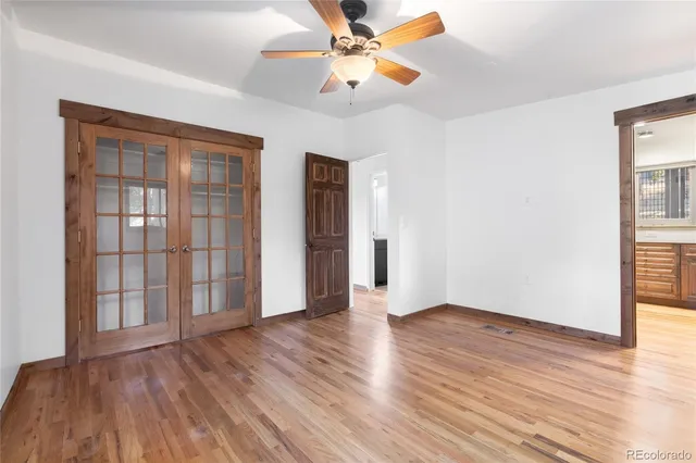 a view of an empty room with window and wooden floor