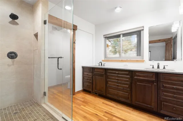 a bathroom with a double vanity sink a mirror and a shower