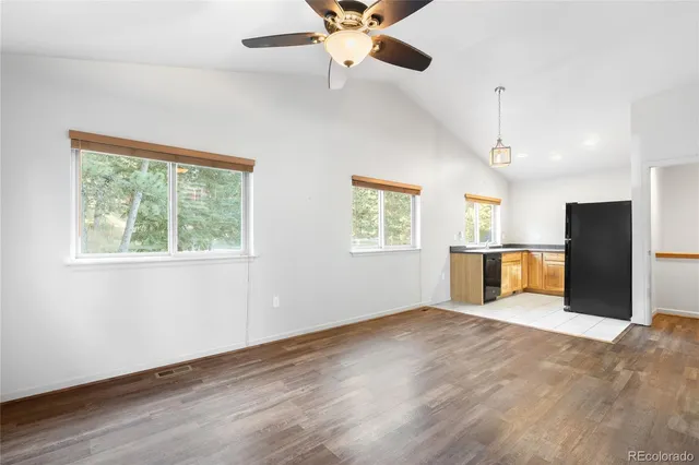 a view of an empty room with a window and a kitchen