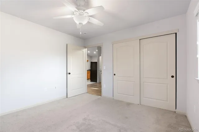 an empty room with a ceiling fan and closet area