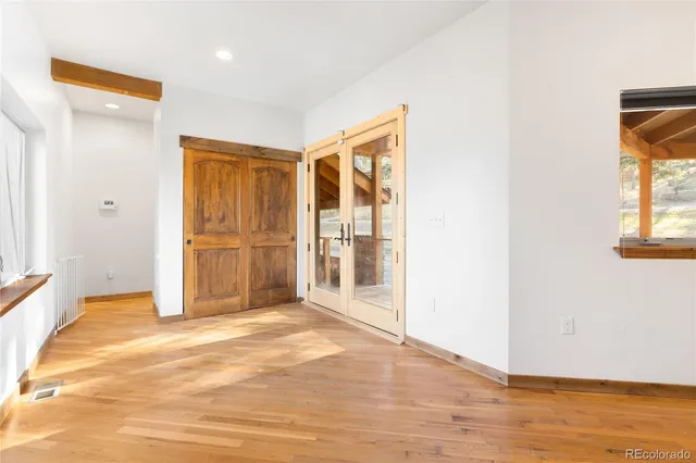 a view of an empty room with wooden floor and a window