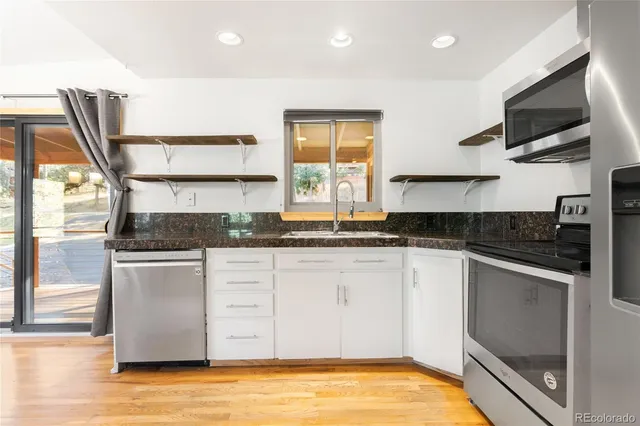 a kitchen with stainless steel appliances granite countertop a stove a sink and a microwave