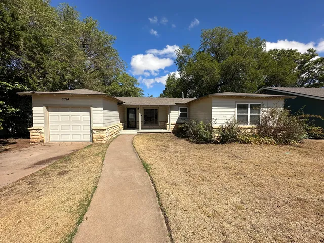 a front view of house with yard and trees around