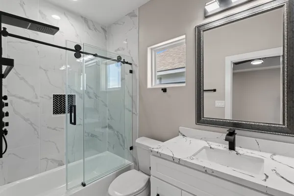 a bathroom with a granite countertop sink toilet and shower