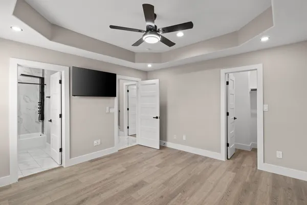 a view of a livingroom with a flat screen tv ceiling fan and wooden floor