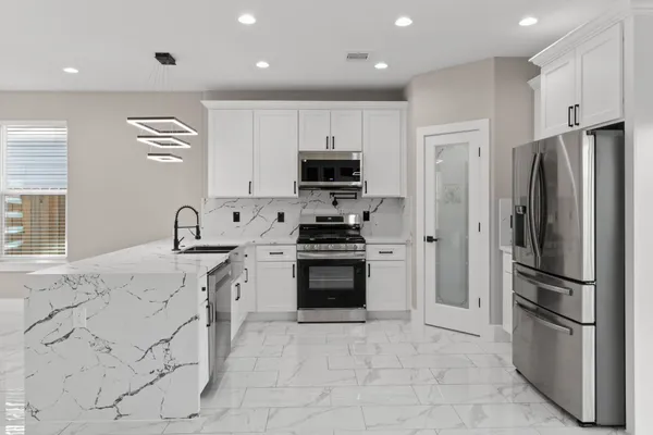 a kitchen with stainless steel appliances granite countertop a refrigerator and a stove top oven