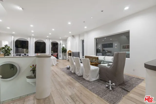 a living room with couches a computer on a desk and kitchen view