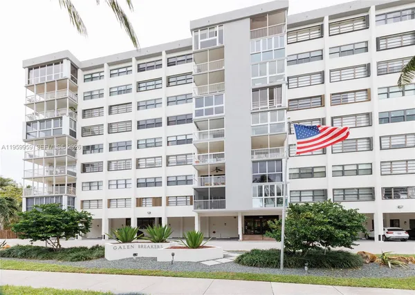 a front view of multi story residential apartment building with yard and sign board