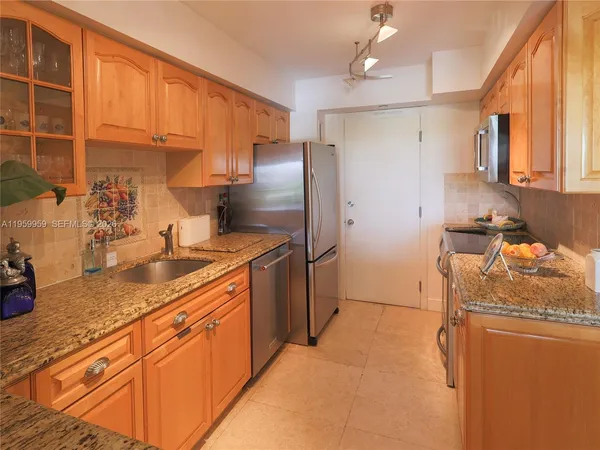 a kitchen with stainless steel appliances granite countertop a sink refrigerator and cabinets