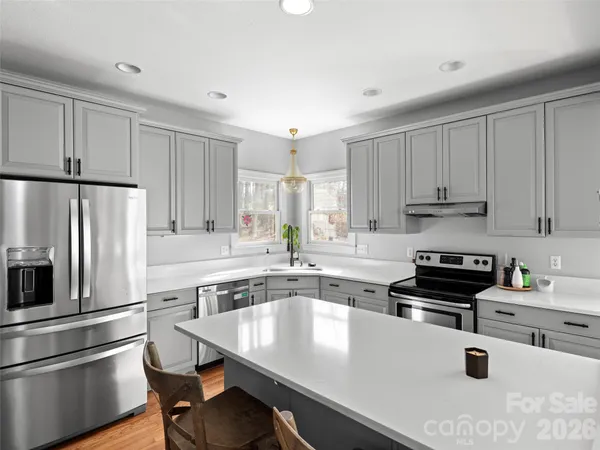 a kitchen with a stove a sink dishwasher and white cabinets with wooden floor