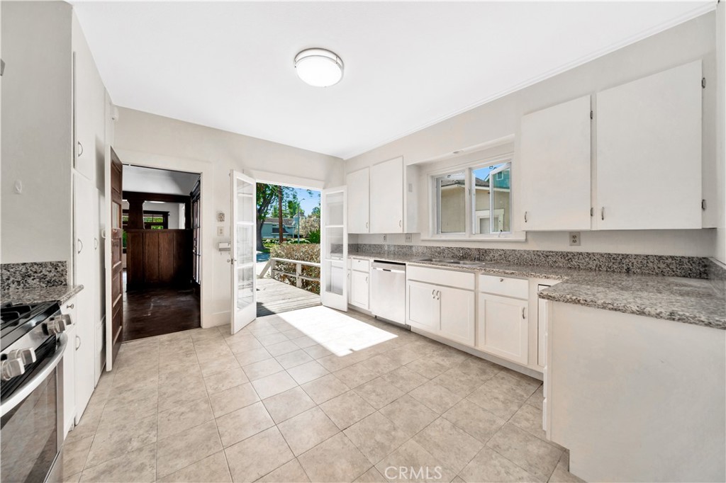 339 South Orange Street Orange, CA 92866 - Photo 19 of 52 a large white kitchen with granite countertop a stove a sink a refrigerator and white cabinets with wooden floor