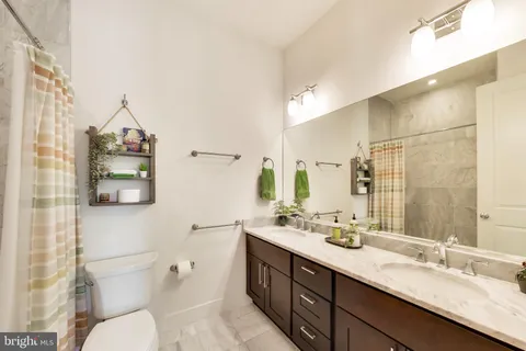 a bathroom with a double vanity sink toilet and a mirror