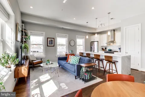 a living room with furniture kitchen view and a large window
