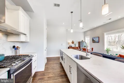 a kitchen with kitchen island a sink a stove and wooden floors