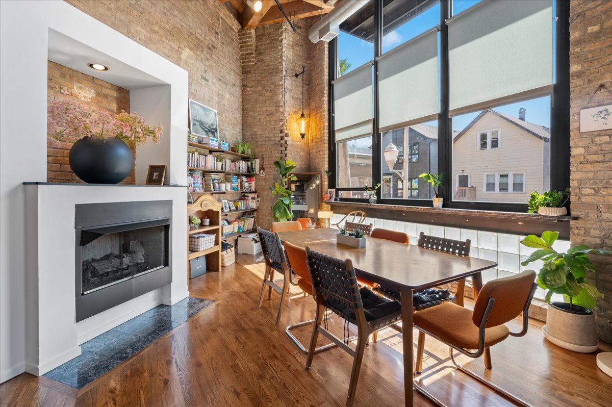 2161 North California Avenue, Unit 105 Chicago, IL 60647 - Photo 6 of 27 a dining room with furniture wooden floor a potted plant and a fireplace