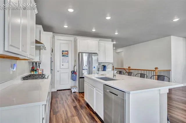 a kitchen that has a lot of cabinets a sink and wooden floor