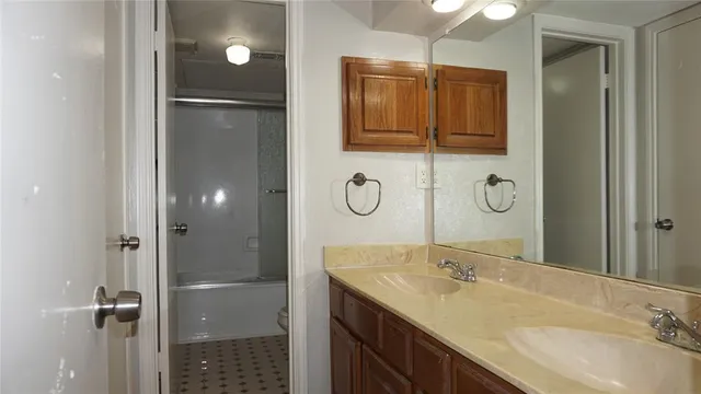 a bathroom with a granite countertop sink a mirror and shower