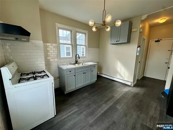a kitchen with stainless steel appliances a sink a stove a refrigerator cabinets and wooden floor