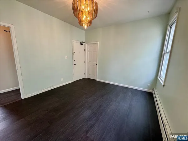 an empty room with wooden floor and mirror