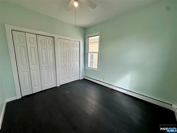 an empty room with wooden floor fan and windows
