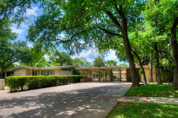 a front view of a house with a yard and a large tree