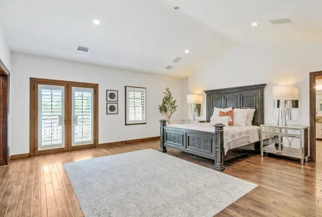a bedroom with a white bed and wooden floor