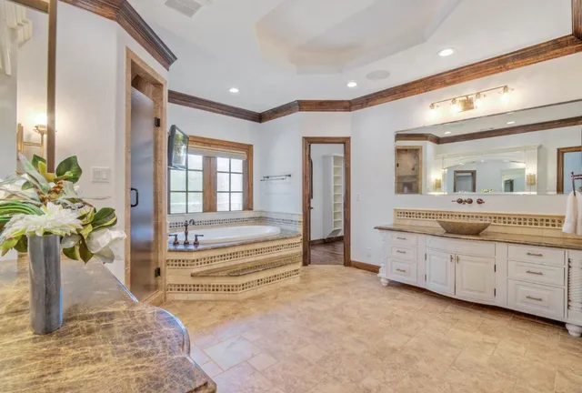 a spacious bathroom with a tub sink and mirror