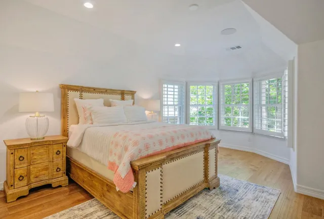 a bed sitting in a spacious bedroom next to a window