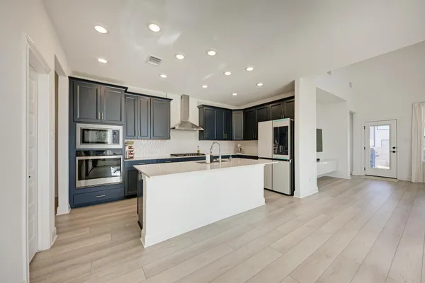 a kitchen with stainless steel appliances kitchen island granite countertop a stove a refrigerator and a microwave oven with wooden floor