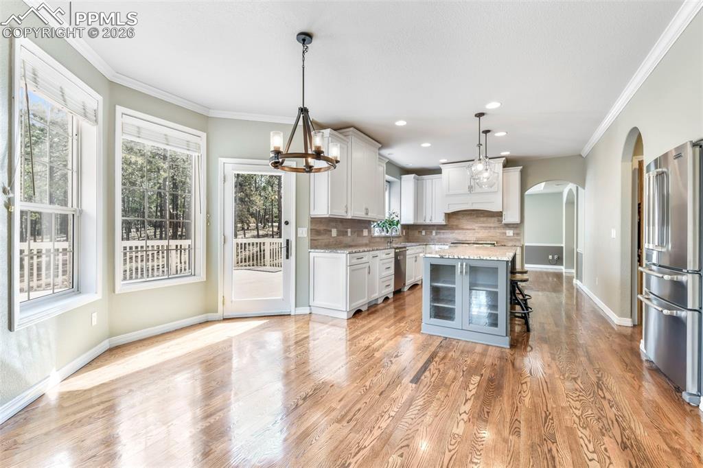 17725 Martingale Road Monument, CO 80132 - Photo 12 of 50 a open kitchen with stainless steel appliances granite countertop a refrigerator a sink dishwasher a stove and a dining table with wooden floor