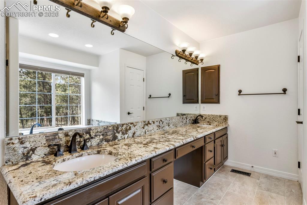 17725 Martingale Road Monument, CO 80132 - Photo 19 of 50 a bathroom with a granite countertop sink and a mirror