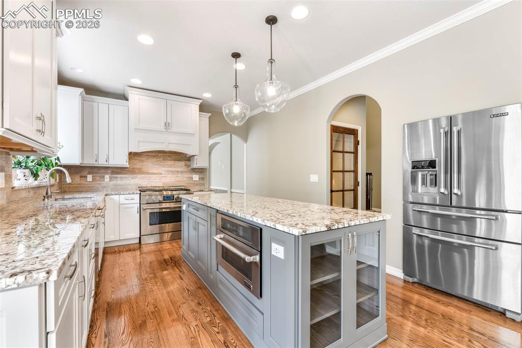 17725 Martingale Road Monument, CO 80132 - Photo 10 of 50 a kitchen with stainless steel appliances granite countertop a stove top oven a sink dishwasher a refrigerator and a dining table with wooden floor