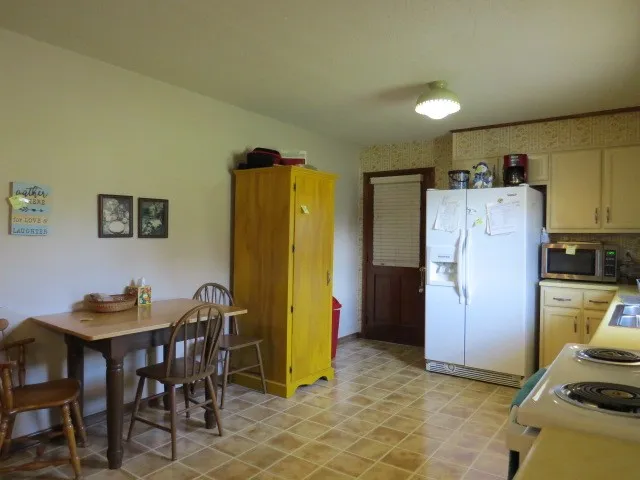a kitchen with refrigerator and chairs