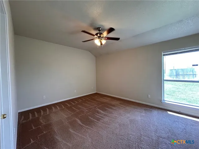 an empty room with a window and a ceiling fan