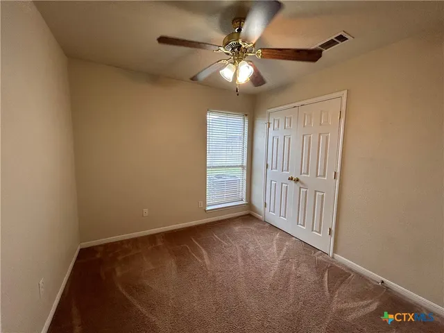 a view of an empty room with a chandelier fan